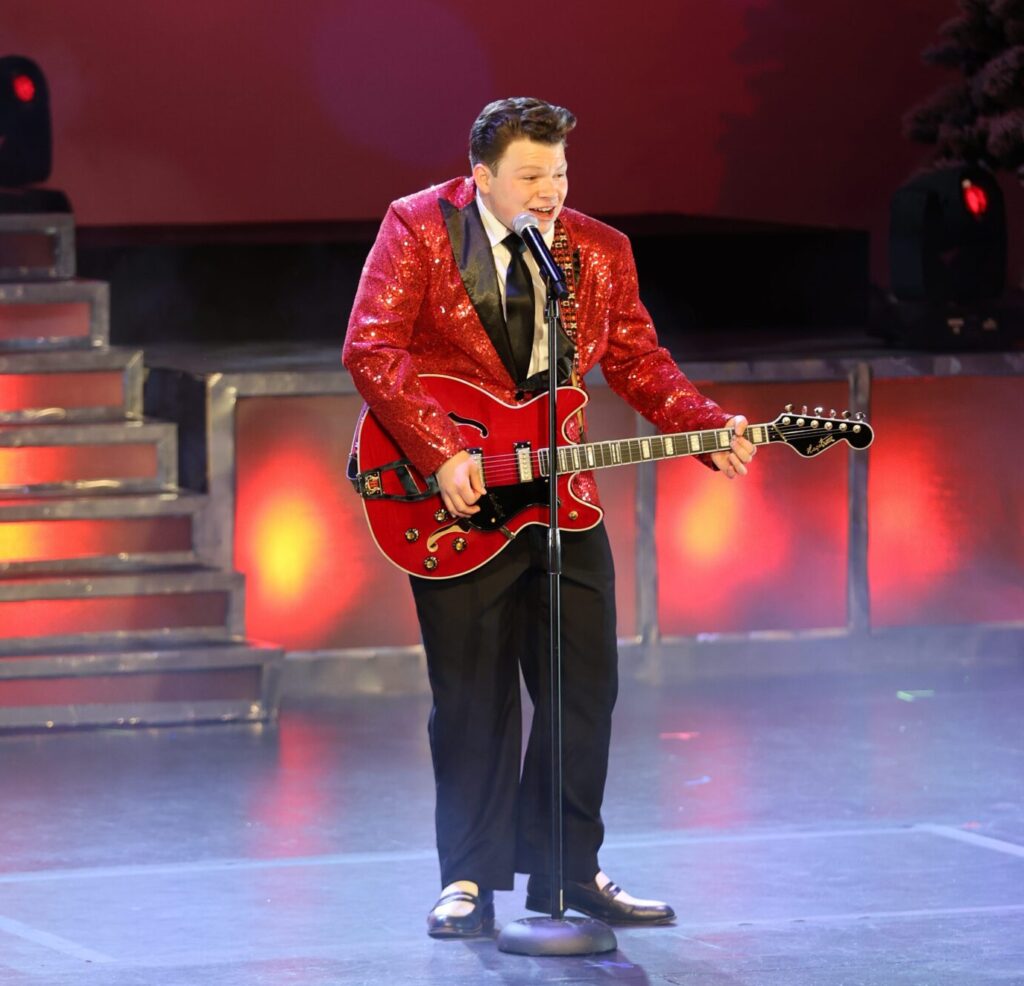 singer in red jacket playing guitar
